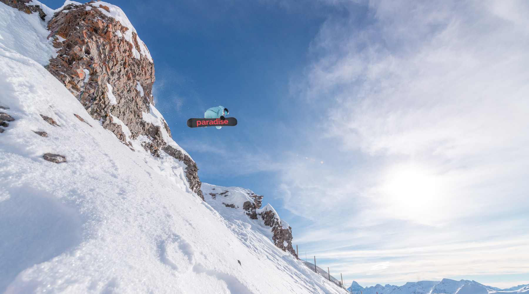 A female snowboarding dropping off a cliff at Banff Sunshine Village 